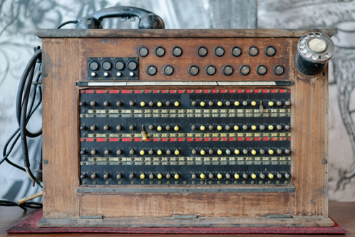 Historische Telefonvermittlung mit Steckfeldern und Telefonhörer, frühe Technik der Netzkommunikation.